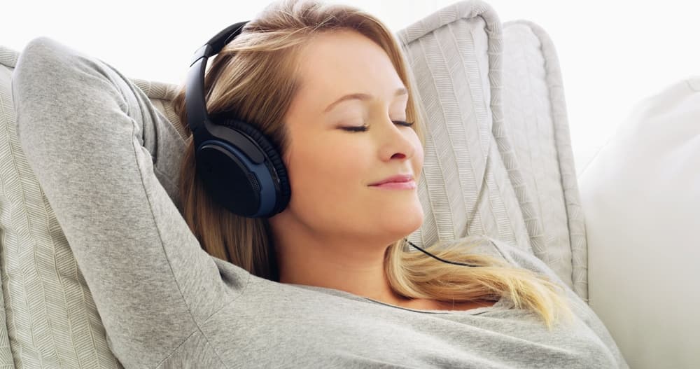 Smiling Young woman lounging on sofa while listening to classical music