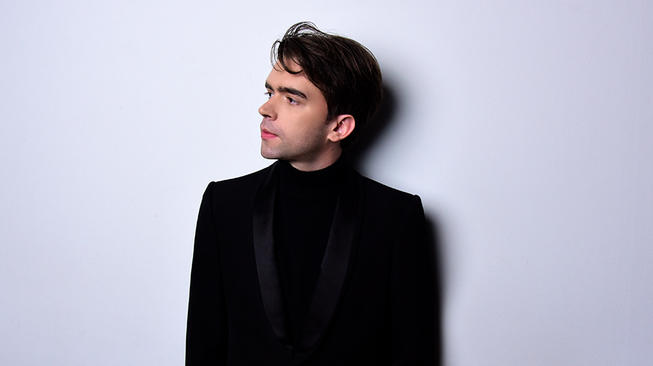 Pianist Albert Cano Smit poses wearing concert black in front of a light gray background.