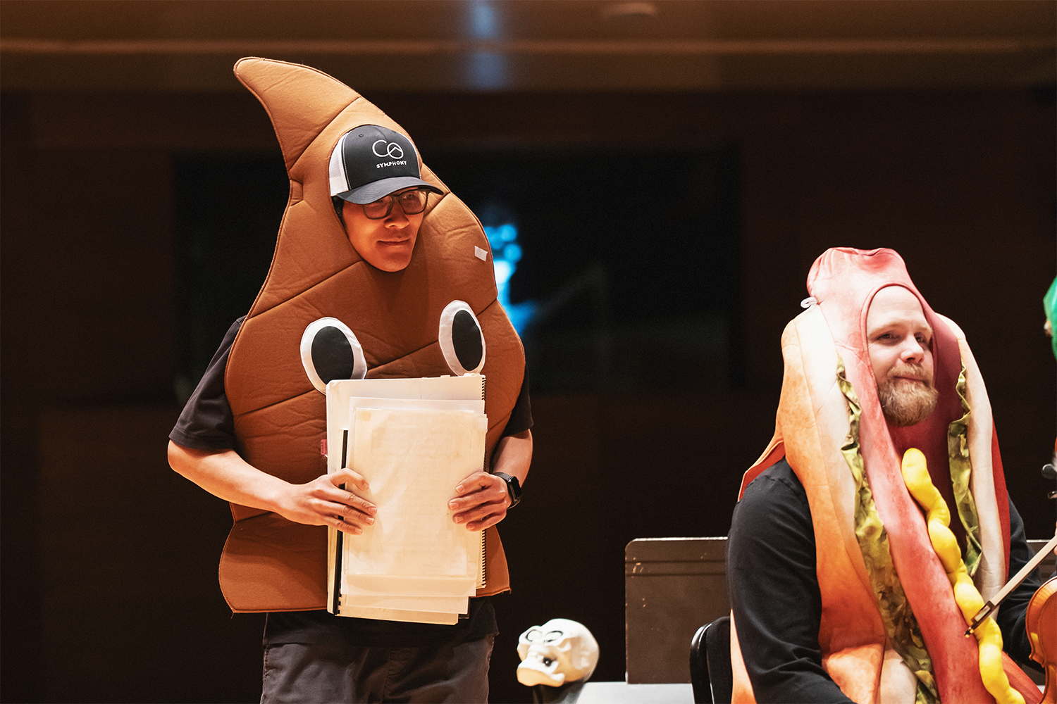Dressed in costume, Orchestra Librarian Lyle Wong walks across stage to place the conductor's score on the podium stand