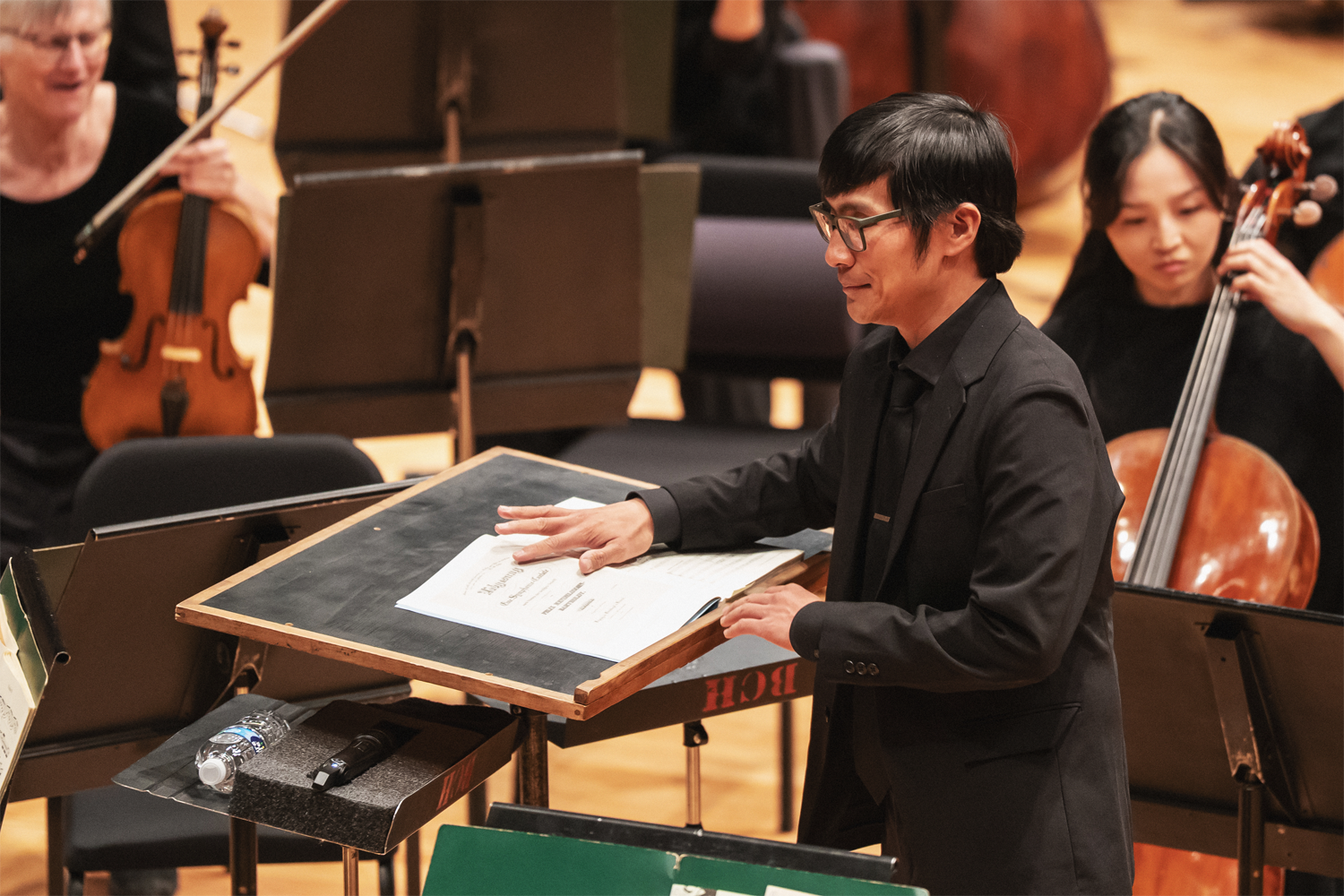 Orchestra Librarian Lyle Wong placing the conductor's score on the podium stand